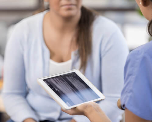podiatrist hold x ray scans of foot and talking to patient